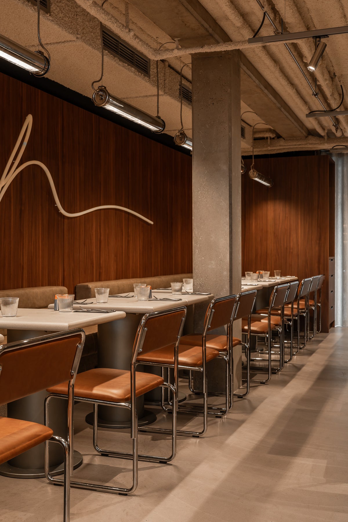 Modern restaurant interior with tables, chairs, and a decorative wall feature.