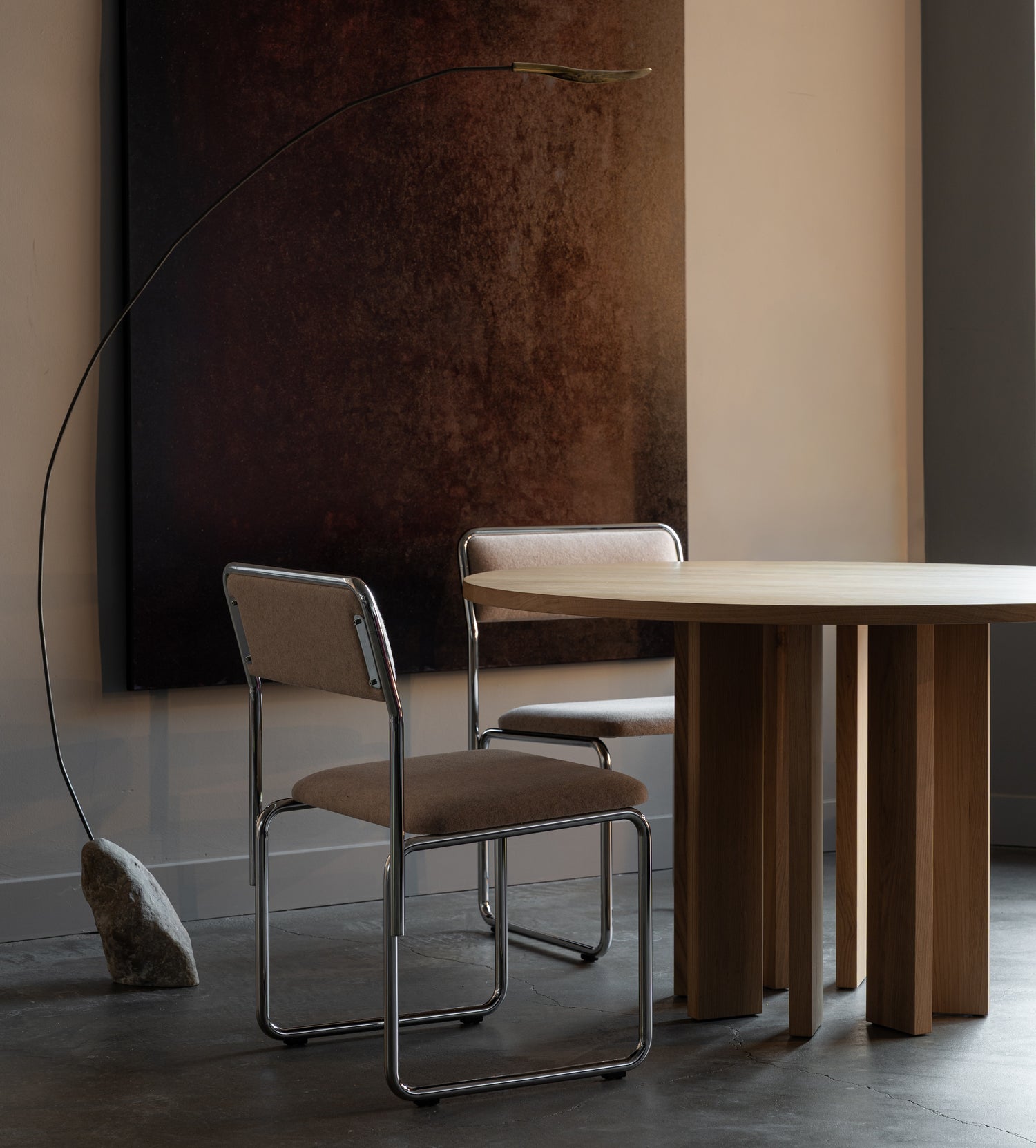 Modern dining area with a round wooden table and chairs in a dimly lit room.