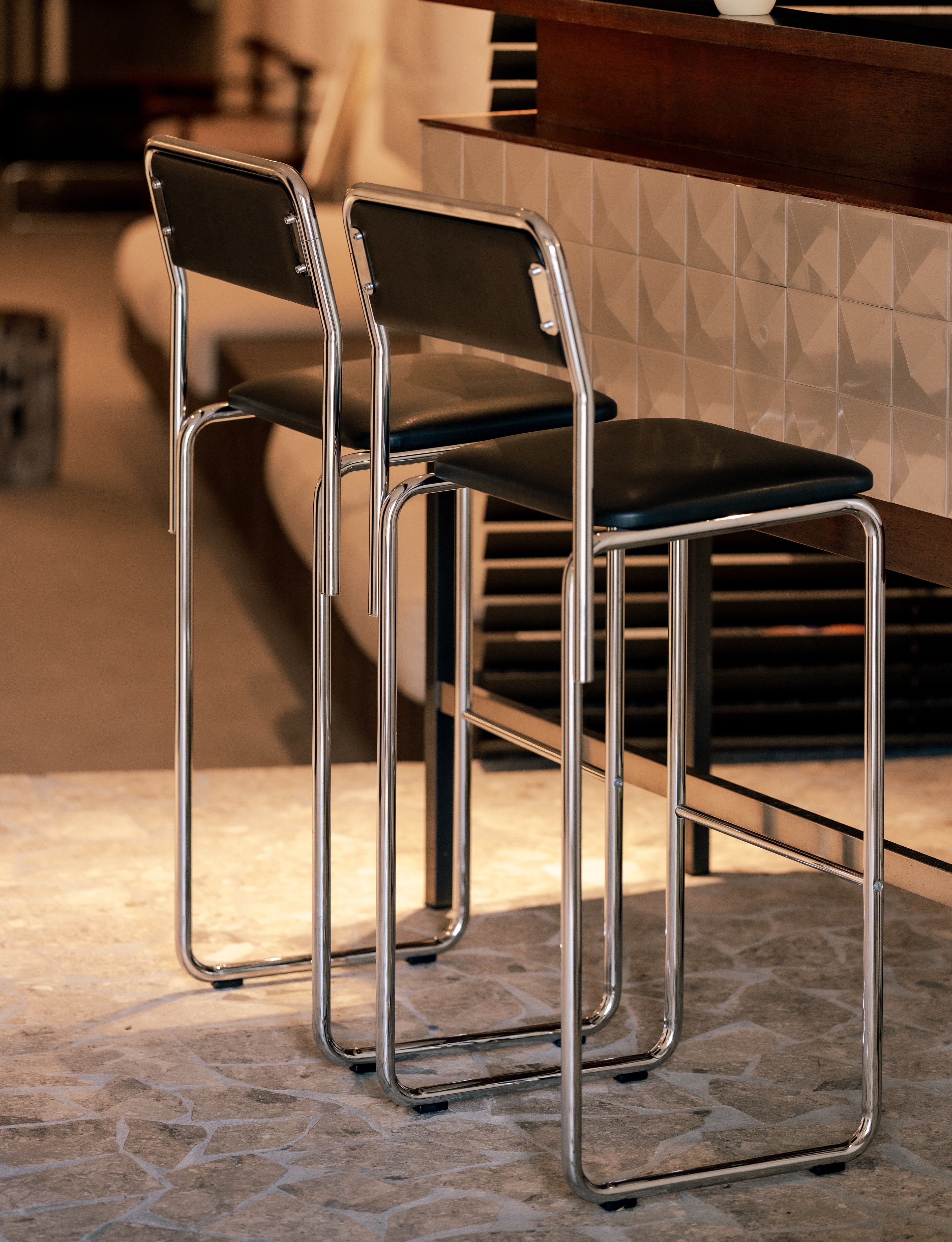 Two black bar stools with chrome frames in a modern interior setting.