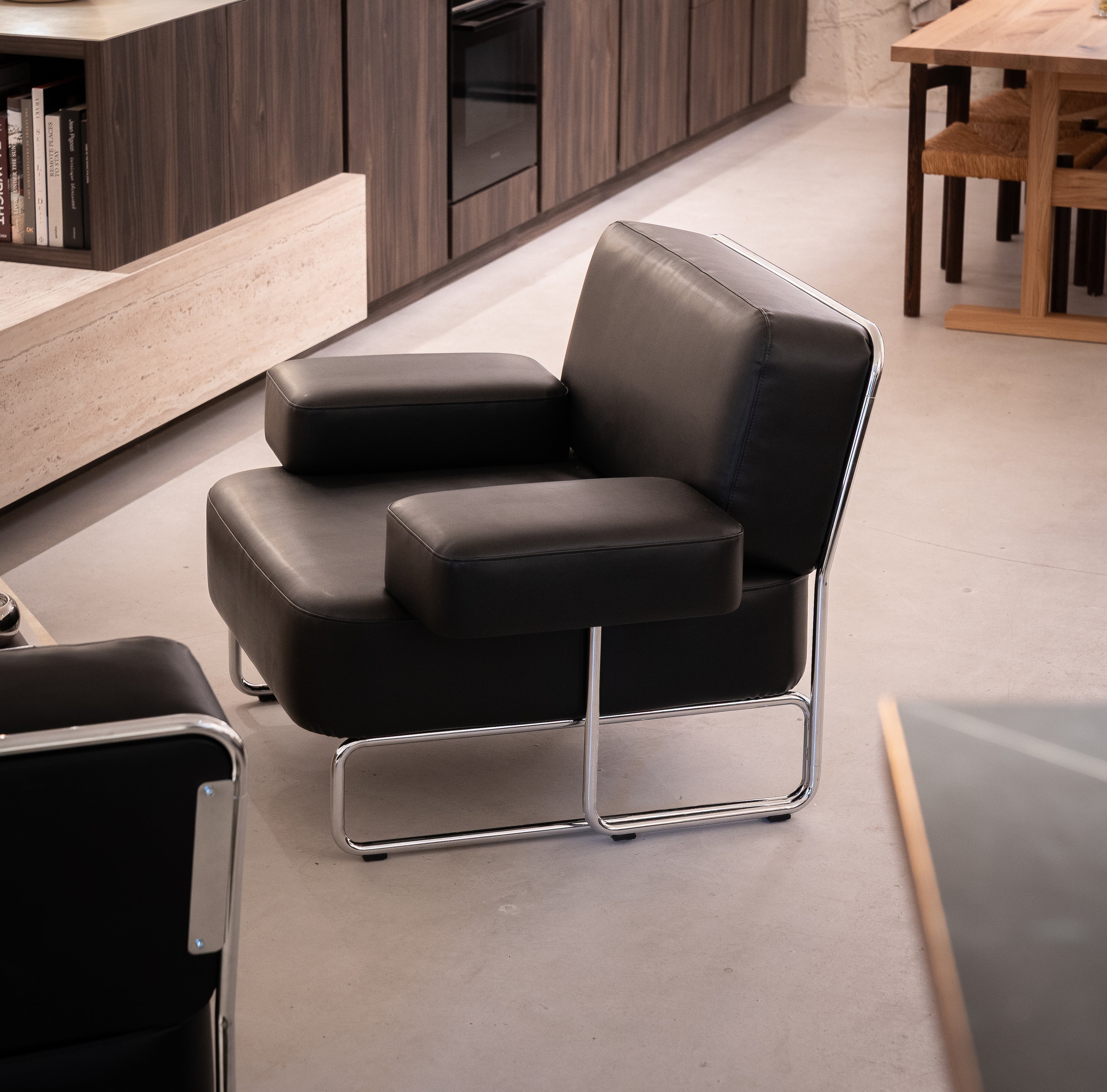 Modern black leather armchair with metal legs in a room setting.